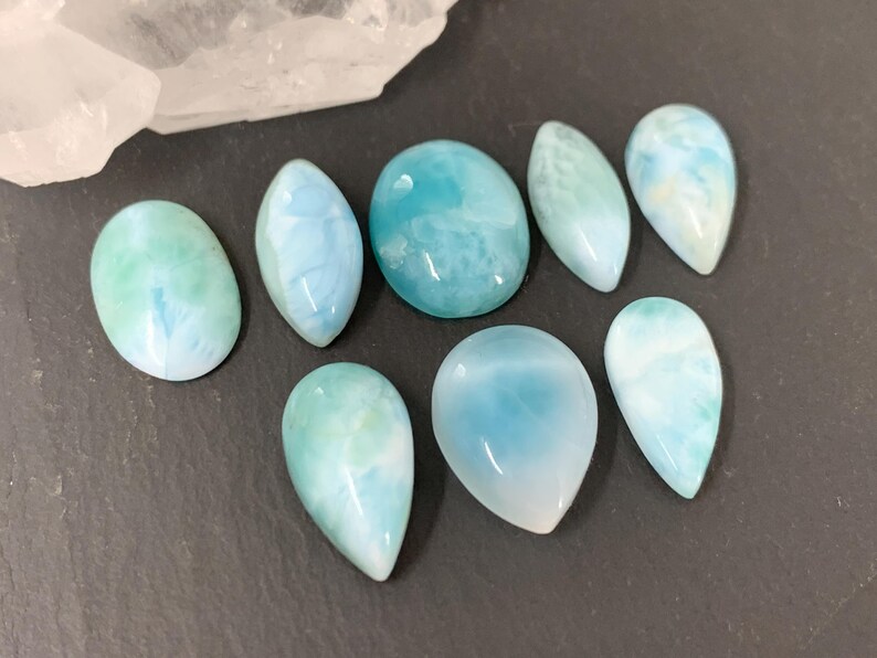 Peut inclure: Une collection de dix pierres pr&eacute;cieuses cabochon bleu clair et blanc avec une finition nacr&eacute;e. Les pierres pr&eacute;cieuses sont de diff&eacute;rentes tailles et formes, y compris en forme de larme et ovale.
