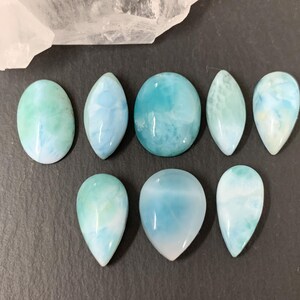 Peut inclure: Une collection de huit pierres pr&eacute;cieuses cabochon bleues et vertes avec un motif marbr&eacute;. Les pierres pr&eacute;cieuses sont de formes vari&eacute;es, notamment ovale, goutte d'eau et ronde.
