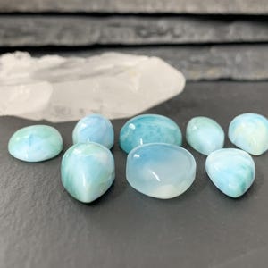 Peut inclure: Une collection de sept pierres pr&eacute;cieuses en cabochon bleues et vertes. Les pierres sont de formes et de tailles vari&eacute;es, certaines ayant une apparence plus opaque que d'autres.