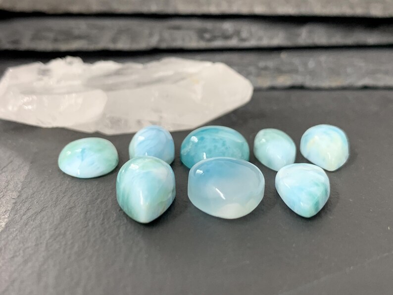 Peut inclure: Une collection de sept pierres pr&eacute;cieuses en cabochon bleues et vertes. Les pierres sont de formes et de tailles vari&eacute;es, certaines ayant une apparence plus opaque que d'autres.