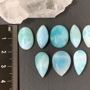 Peut inclure: Neuf pierres pr&eacute;cieuses en cabochon de diff&eacute;rentes formes et tailles, notamment ovales, en forme de larme et rondes. Les pierres sont de couleur bleu clair avec des tourbillons et des motifs blancs et verts.