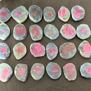 May include: Twenty-four natural gemstone cabochons, each with a unique pink and blue color pattern. The cabochons are smooth and polished, with a slightly irregular shape. They are ideal for jewelry making or crafting.
