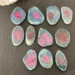 May include: Assortment of 10 pink and blue gemstone cabochons. The cabochons are irregularly shaped and have a smooth, polished surface.