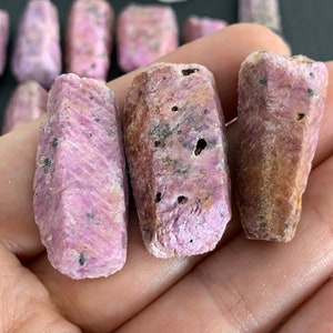 以下が含まれることがあります： ピンクのルビーの原石の集合。結晶は未加工で、自然な研磨されていない仕上げになっています。鮮やかなピンクの色で、さまざまな形とサイズがあります。