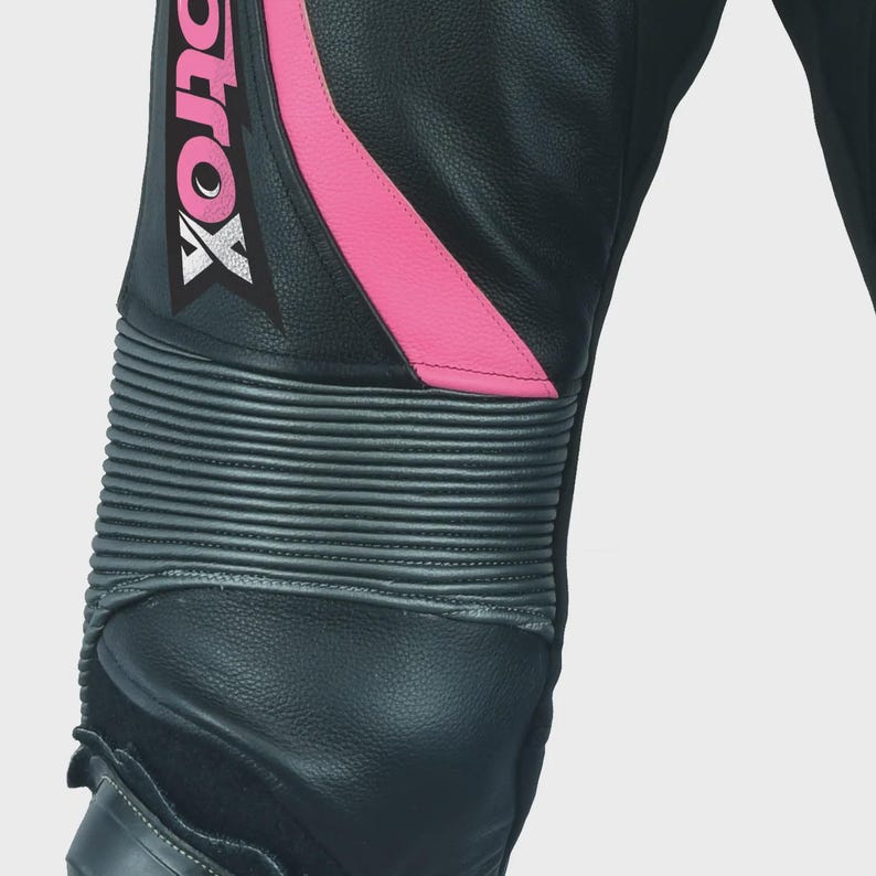 May include: Close-up of black leather motorcycle pants with pink accents and the word "MotoX" printed on the side. The pants have knee pads with a textured design.