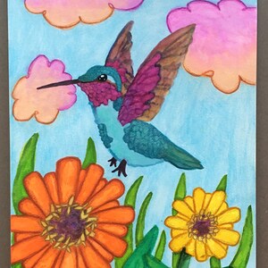 May include: A watercolor painting of a hummingbird in flight, with a blue body, purple wings, and a long black beak. The background features pink clouds and a light blue sky. Orange and yellow flowers are in the foreground.
