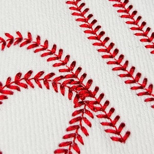 May include: Close-up of white fabric with red stitching in a baseball pattern. The red stitching is thick and detailed, creating a textured effect. The image highlights the classic design of a baseball.