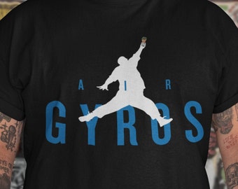 May include: A black t-shirt with a white silhouette of a person holding a gyro. The text "AIR GYROS" is printed in blue letters below the silhouette.