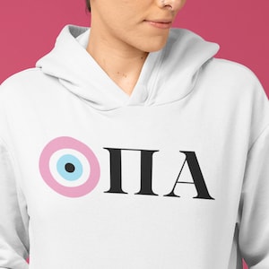 Peut inclure: Sweat-shirt blanc avec un motif œil maléfique rose et bleu et le mot "OPA" en texte noir.