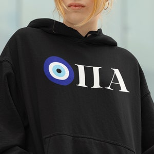 Peut inclure: Sweat-shirt à capuche noir avec un texte "OPA" blanc et un graphique d'œil maléfique bleu.