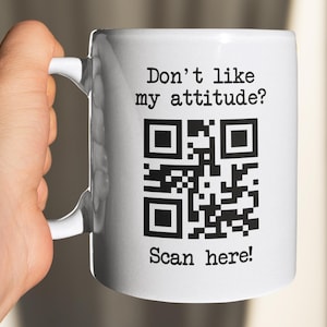 Op de afbeelding: Witte keramische mok met zwarte tekst die "Don't like my attitude? Scan here!" zegt en een zwart-witte QR-code.
