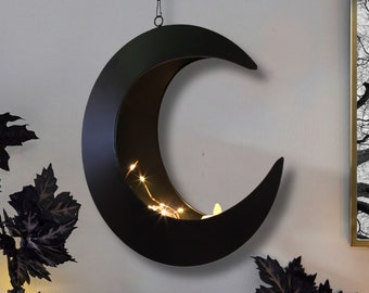 May include: Black metal crescent moon wall decor with a cutout design and string lights inside.
