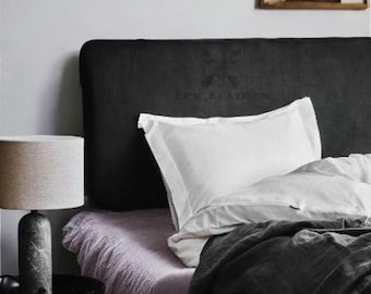 Könnte beinhalten: Schlafzimmer-Interieur mit einem Bett mit schwarzem Kopfteil und weißer Bettwäsche. Eine graue Decke und eine hellviolette Tagesdecke sind zu sehen. Eine Marmorlampe steht auf einem schwarzen Beistelltisch. Der Text "EPIC LEATHER" ist auf dem Kopfteil.