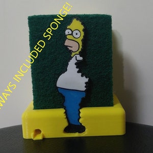 Puede incluir: Porta esponjas amarillo con una esponja verde y un personaje de dibujos animados de Homero Simpson de Los Simpsons. El texto "ALWAYS INCLUDED SPONGE!" está impreso en el lateral del porta esponjas.