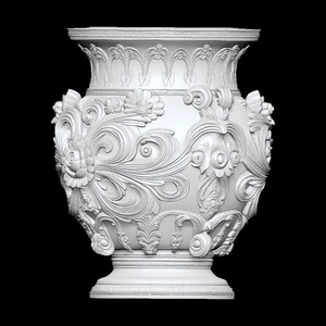 Pu&ograve; includere: Un vaso bianco e ornato con dettagliati disegni floreali e a volute. Il vaso ha una parte superiore ampia e svasata e una base a piedistallo. Le sculture a rilievo creano un effetto tridimensionale, mostrando l'intricata maestria artigianale. Lo sfondo &egrave; nero.