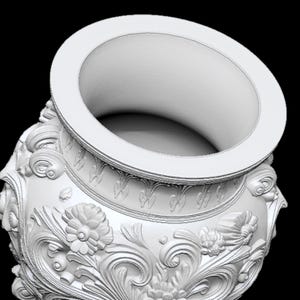 Pu&ograve; includere: Un vaso bianco e ornato con un'ampia apertura e dettagli floreali e a volute in rilievo. Il vaso ha un bordo spesso e una superficie strutturata, che mostra un design classico. Lo sfondo &egrave; nero.