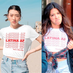 May include: White cropped t-shirt with the text "LATINA AF" repeated in red lettering. The text "Have a Nice Day" is printed at the bottom of the shirt.