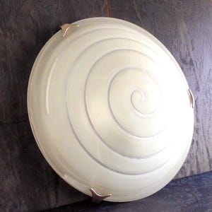May include: A white ceiling light fixture with a spiral design and silver accents. The light fixture is round and has a frosted glass shade.