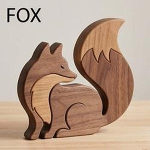 May include: A wooden fox figurine crafted from two distinct shades of brown wood, featuring a dark brown body and a lighter brown chest and tail tip. The word FOX is printed in black in the upper left corner of the image.