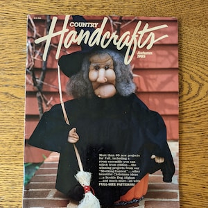 May include: A magazine cover featuring a witch doll with a broom. The magazine is titled "Country Handcrafts" and the issue is from Autumn 1985. The text on the cover reads "More than 40 new projects for Fall, including a room ensemble you can stitch from ribbon...the winning projects from our "Stocking Contest"...other beautiful Christmas ideas...a Scottie Dog Afghan...and much more-all with FULL-SIZE PATTERNS!"