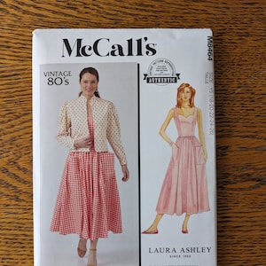 May include: Vintage McCall's sewing pattern for a dress and jacket. The pattern is for sizes Y5 (18-20-22-24-26) and is a Laura Ashley design. The pattern features a red and white gingham dress and a white polka dot jacket.
