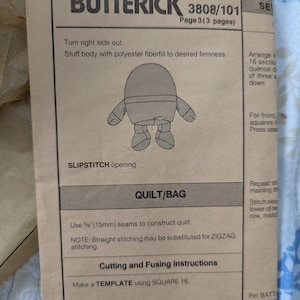 May include: A vintage Butterick sewing pattern, model 3808/101, for a quilt or bag. The instructions include cutting and fusing details, with measurements in inches and centimeters. The pattern features a drawing of a stuffed figure.