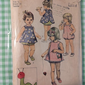 May include: Vintage Simplicity sewing pattern 8812 for toddler dresses. The pattern features illustrations of children's dresses with floral and gingham designs. Includes a transfer for an applique. The pattern is for size 1/2, breast 19 inches.