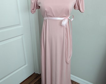 Könnte beinhalten: Ein langes, rosafarbenes Maxikleid mit hohem Kragen und kurzen Puffärmeln. Das Kleid hat eine Schärpe, die in der Taille gebunden wird.