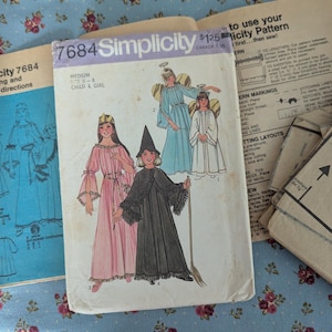 May include: Vintage Simplicity sewing pattern 7684 for children's costumes. The pattern features illustrations of angel and witch costumes. The pattern includes cutting and sewing directions. The pattern is on a floral background.
