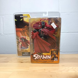 May include: A Spawn action figure in a clear plastic package. The figure is black and red, with a flowing cape. The packaging features the Spawn logo and the text "Classic Comic Covers". A second package is visible in the background.