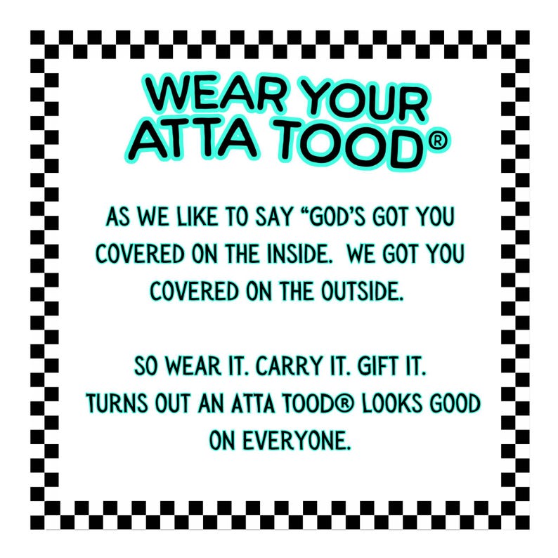 May include: White rectangular sign with a black and white checkered border. The text "WEAR YOUR ATTA TOOD" is in turquoise, with additional text below. The sign encourages the reader to wear, carry, and gift the product.