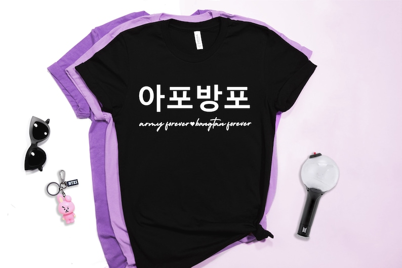 K&ouml;nnte beinhalten: Schwarzes T-Shirt mit wei&szlig;em Text, der "아포방포 army forever &hearts; bangtan forever" lautet. Das Shirt ist gefaltet und auf einem violetten Hintergrund abgebildet.