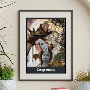 May include: Framed art print featuring a collage with a woman's portrait, a crown, and floral elements. The artwork includes a hand with an eye and the text "The high priestess" at the bottom. The print is displayed on a wooden shelf.