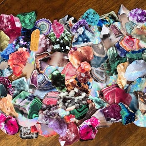 Puede incluir: Una colección de piedras preciosas de colores, cortadas y pulidas. Las piedras son de varias formas y tamaños, incluyendo amatista, ágata y malaquita.