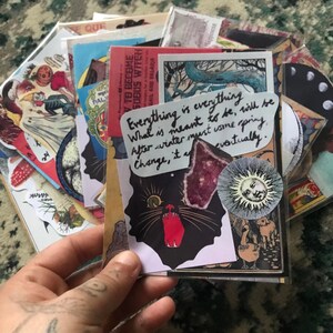 May include: A collection of vintage ephemera and stickers featuring a black cat with red eyes, a sun with a face, and a quote that reads "Everything is everything. What is meant to be, will be. After winter must come spring. Change, it a... eventually."