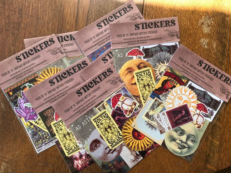 May include: A set of ten vintage witchy stickers featuring a variety of designs, including a sun, moon, mushrooms, and a crystal. The stickers are printed on brown paper with the text "PACK OF 10 VINTAGE WITCHY STICKERS" printed on each sheet.