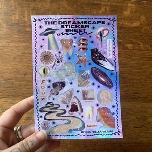 Op de afbeelding: Een stickerblad getiteld "The Dreamscape Sticker Sheet" met diverse hemelse en surrealistische illustraties. Het blad bevat afbeeldingen van een ruimteschip, ogen, tanden, een melkwegstelsel en de tekst "Lady of the Moon".