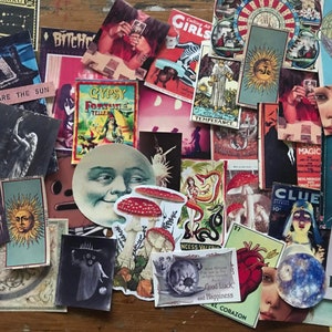 May include: A collection of vintage and modern stickers featuring various designs, including a moon face, mushrooms, a heart, a sun, a snake, a woman, and a tarot card. The stickers are on a wooden surface.