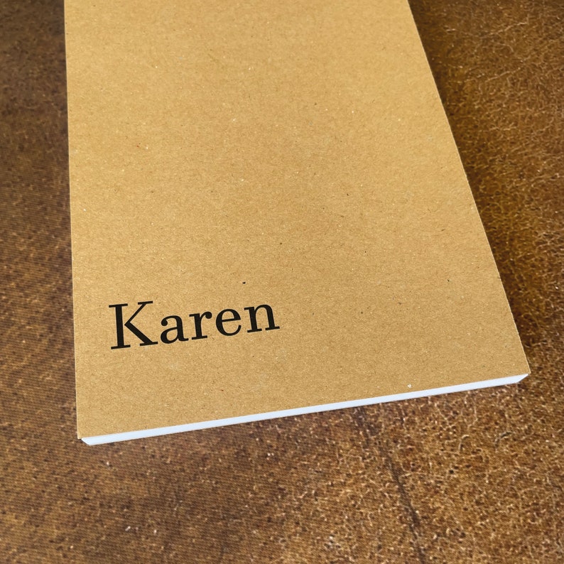 K&ouml;nnte beinhalten: Ein braunes Notizbuch mit dem Namen "Karen" auf dem Einband.