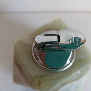 Puede incluir: Un encendedor de mesa de m&aacute;rmol verde con una tapa plateada. La tapa tiene las palabras "DANDY" y "LONDON" grabadas.