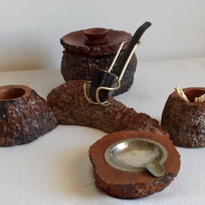 May include: A wooden smoking set with a pipe, ashtray, match holder, and a small jar. The set is made of wood that looks like tree bark.