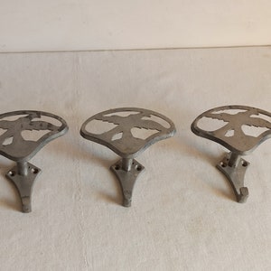 Può includere: Tre ganci da parete in metallo color argento. Ogni gancio presenta un design traforato di un uccello in volo. I ganci sono montati su una piccola base quadrata con fori per le viti e hanno un singolo gancio sotto.