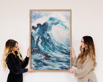 Peut inclure: Grande œuvre d'art encadrée représentant une vague océanique déferlante dans des tons de bleu et de blanc. La peinture est tenue par deux personnes contre un mur blanc. Le cadre est de couleur bois clair.