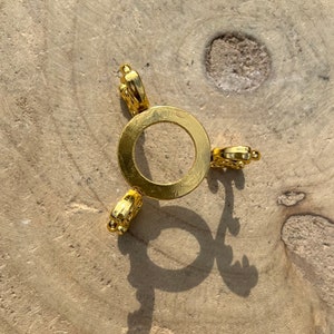 Pode incluir: Um suporte decorativo de metal dourado com uma parte superior redonda e três pernas. Cada perna tem um design decorativo.