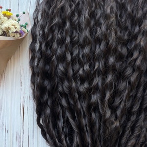 May include: A close-up of a bundle of dark brown curly hair extensions. The hair is arranged in a loose, flowing style, showcasing its natural texture and volume.