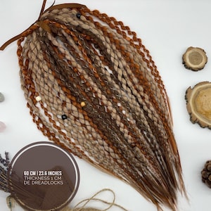 May include: A bundle of double-ended dreadlocks in shades of brown, tan, and copper, tied with a brown ribbon. The text on the image reads: 60 cm | 23.6 inches, Thickness 1 cm, DE Dreadlocks.