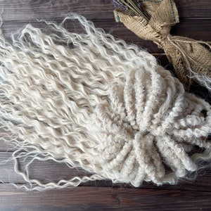 May include: A bundle of long, white, curly hair extensions. The hair is arranged in a loose, circular shape.