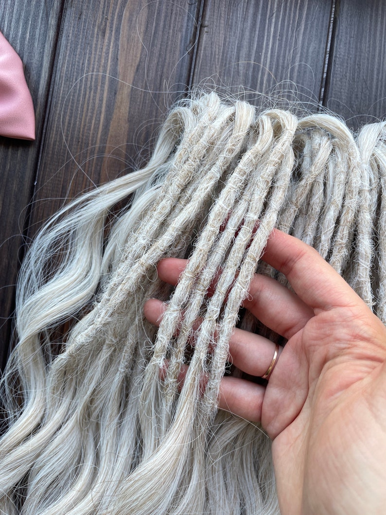 May include: A bundle of light blonde synthetic dreadlocks. The dreadlocks are made of a soft, textured material and are approximately 24 inches long.