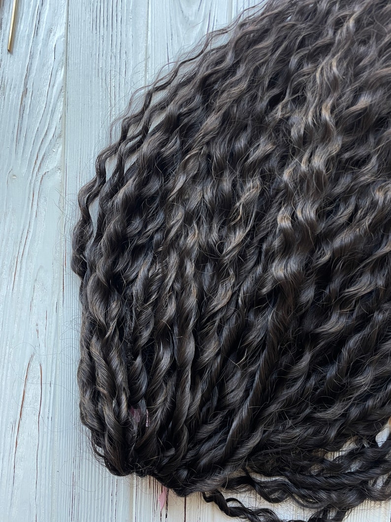 May include: A close-up of a bundle of dark brown curly human hair extensions. The hair is arranged in a loose, wavy pattern, showing the texture and thickness of the strands.