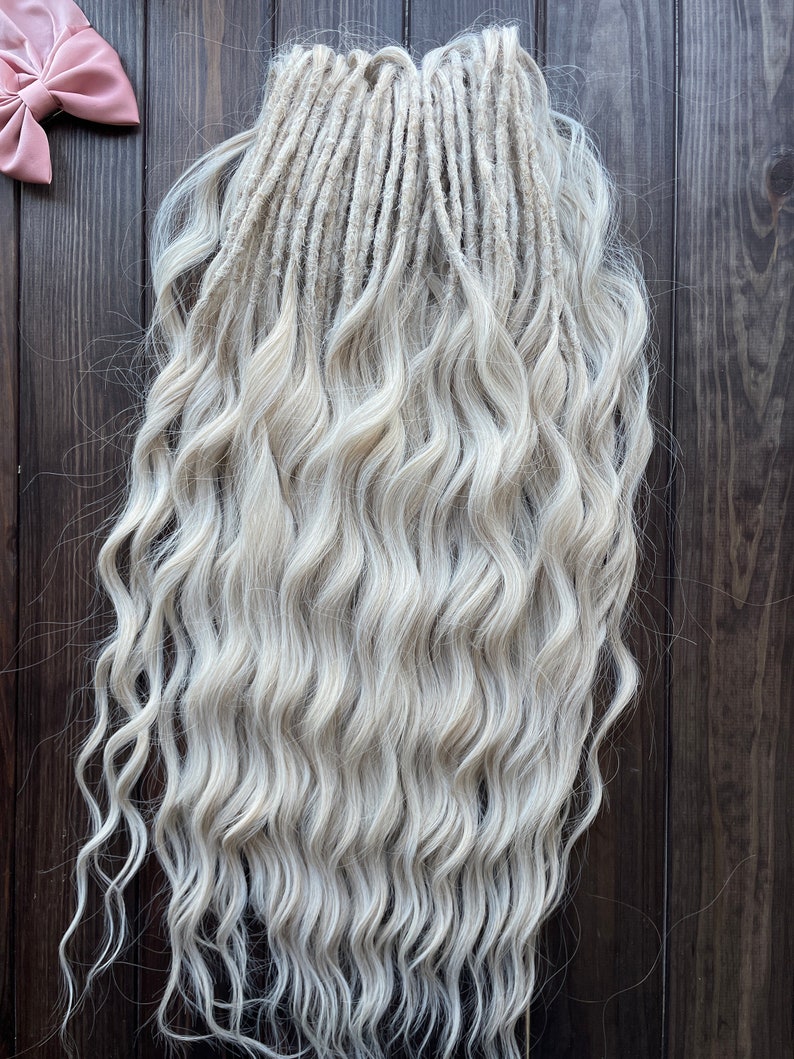 May include: A set of long, wavy, white synthetic dreadlocks. The dreadlocks are arranged in a straight line and are hanging down.